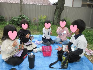 ブルーシートに座り花見をしている園児たちの写真