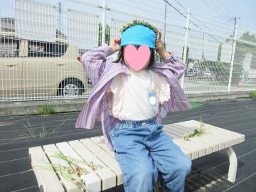 フェンスの前のベンチに座り髪飾りをかぶる園児の様子