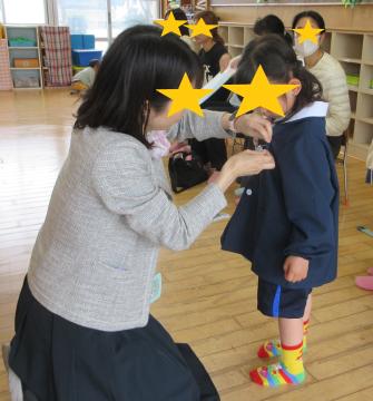 担任に名札をつけてもらう5歳児ぶどう組