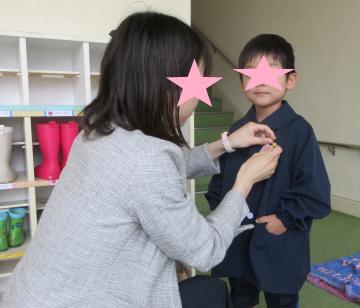 担任に名札をつけてもらう、入園式に参加する4歳児いちご組の子ども