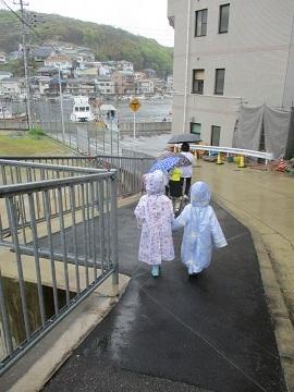雨の中、カッパを着てパンを買いに行く園児たちの様子