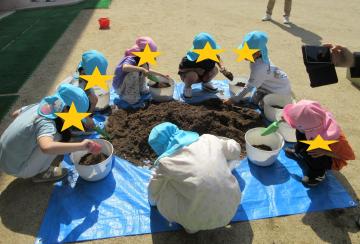 植木鉢に土を入れている幼児
