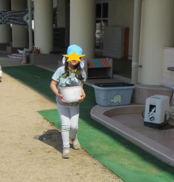 野菜を植えた鉢を運ぶ幼児