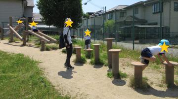 大型アスレチックに挑戦している子ども達と見守る教師