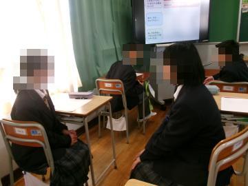 教室で、生徒が椅子を向かい合わせにし、隣の席の生徒と話をしています。