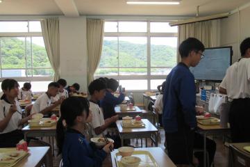 教室で、8年生が給食を楽しんでいる様子