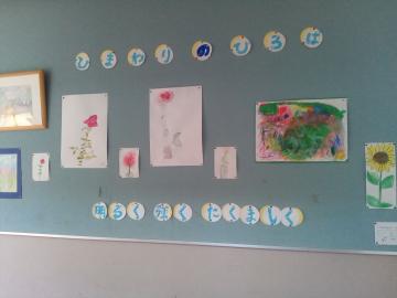 教室の掲示板に子どもの絵や色紙がピンで貼られ丸い名前札が並んでいる