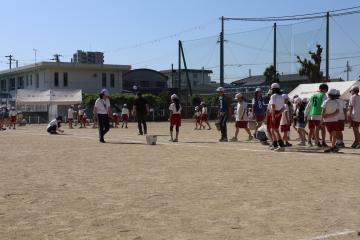 縦割り班で運動場を掃除している写真