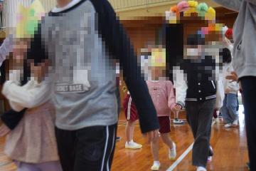 体育館内で、6年生と手をつなぎ入場する1年生の児童たちの様子