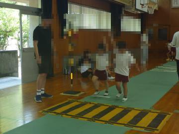 体育館に設置された模擬踏切を渡る練習をする児童たちの様子