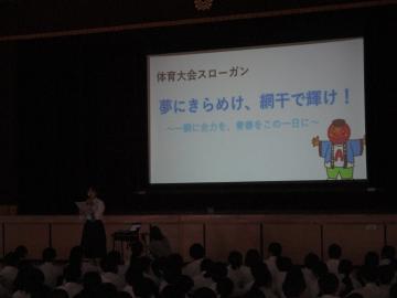体育館で、生徒会の生徒がオリエンテーションで他の生徒たちに説明する様子