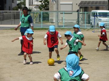 ビブスを着用し、サッカーの試合を行い、ボールを取り合っている様子
