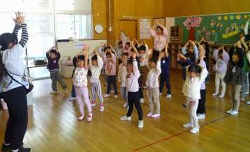 室内で園児たちが音楽に合わせてみんなで踊っている様子