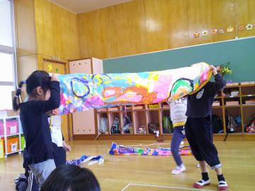 室内で園児たちがこいのぼりを両端から覗いている様子