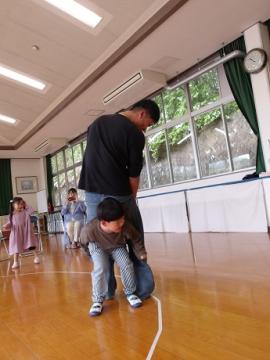 室内で幼児と幼児のお父さんがしりずもうをする様子