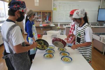 6年生が炒めた野菜をお皿に盛り付けている様子