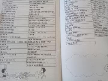 冊子の見開きページに細かな日本語の一覧表が左右に並び下部に子供のイラストが描かれている