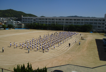 全校生徒が運動場に集合し、体育大会開会式の練習を行っている様子
