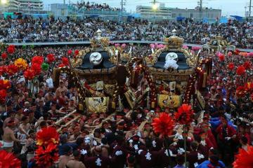 大勢の人々が伝統的な飾りつきの御輿を担いでいる祭りの屋外の賑やかな光景