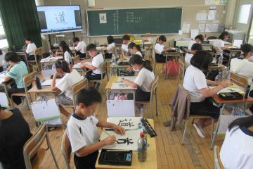 5年生が筆を使って「道」という字を書いている様子