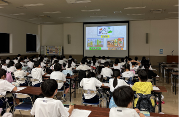 4年生が座って、ごみの分別についてのスクリーン画像を見ている