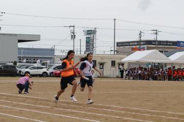 女子リレーでバトンをもって走る生徒たち