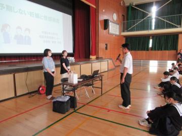 出前授業の終わりに、体育館の壇上前で、講師の保健師さん2名にお礼の言葉を生徒が述べている様子