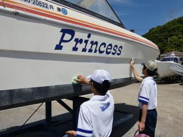 白い制服と帽子を着た二人が係留された船の側面に書かれた英字の船名Princessを布で拭いている光景