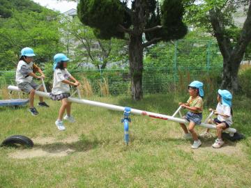 公園でシーソーに乗っている園児たち