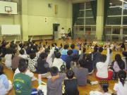 体育館の床に座った多数の子どもたちの集会の様子