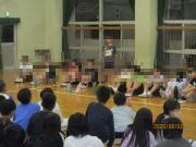 体育館で床に座る多数の子供たちの集会風景