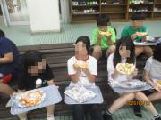 ベンチに座ってピザを食べている児童たち
