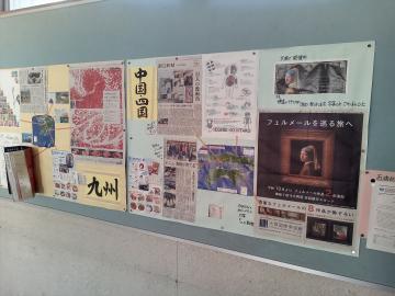 屋内の掲示板に九州の観光情報やイベント案内と思われるポスターや記事が複数貼られている様子