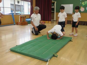 マットで男の子が一人前転をしようとしている様子