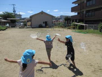 シャボン液のついたうちわを振り、たくさんのシャボン玉を作ろうとしている様子