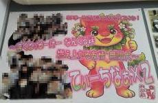 ピンクの笑顔のキャラクターが描かれた看板にモザイクでぼかされた人物写真とピンクの装飾文字が配された広告