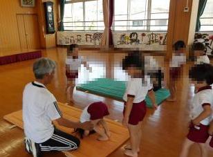 室内で4歳児がマットで前転をしている様子