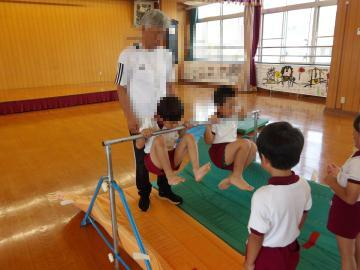 室内で5歳児が鉄棒から落ちないように力を振り絞っている様子