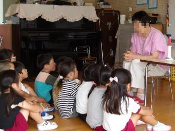 室内で5歳児がお話の先生の素話を聞いている様子