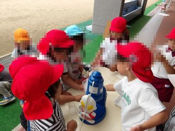 園庭で、出来ている色水をかき氷にして遊んでいる様子