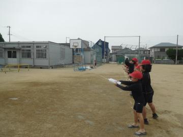 校庭で赤い帽子をかぶった子どもたちが水を飛ばしている
