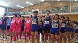 屋内の体育館でゼッケンを付けた青と赤のユニフォームを着た中高生らしき男女が整列している