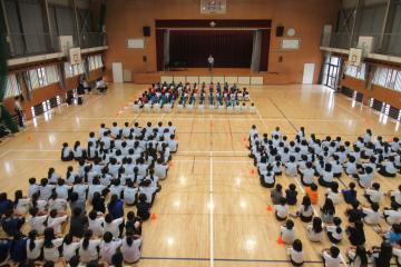 校長先生が運動部選手に激励の言葉を話され、5年生から9年生が集中して聴いている様子