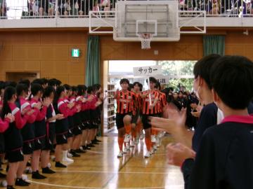 体育館に選手が入場する様子です。参加者が拍手で迎え入れています。