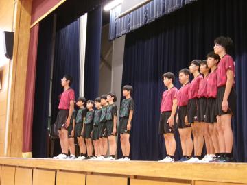 体育館の壇上で、男子卓球部の生徒たちが決意表明をしている様子