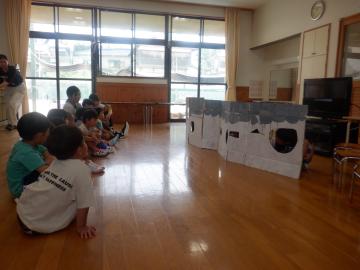 ダンボールで作った城壁の穴からのぞき込む子供たち