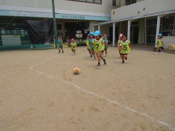ビブスを着てサッカーボールを蹴ろうと追いかける子供たち
