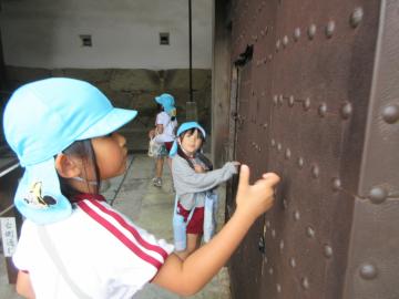 姫路城の門にノックをして固さを確かめる子供