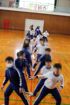 6年生が体育館で縦に並び集合写真を撮っている様子