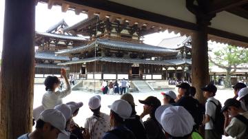 法隆寺の前でバスガイドに児童が説明を受けている様子